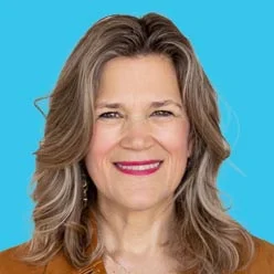 Smiling woman with shoulder-length brown hair in a brown top, against a bright blue background.