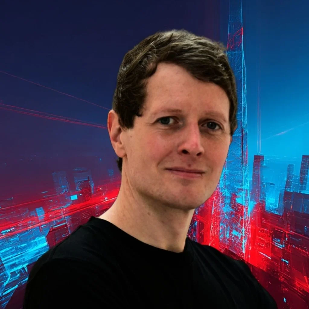 Portrait of a man with short brown hair in a black shirt, in front of a neon blue‑red cityscape backdrop.