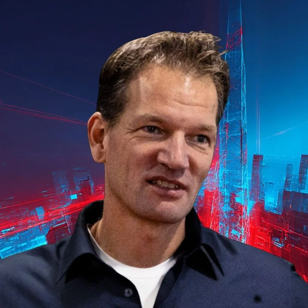 Man in a dark button-down shirt, smiling slightly, against a blue‑red neon cityscape backdrop.